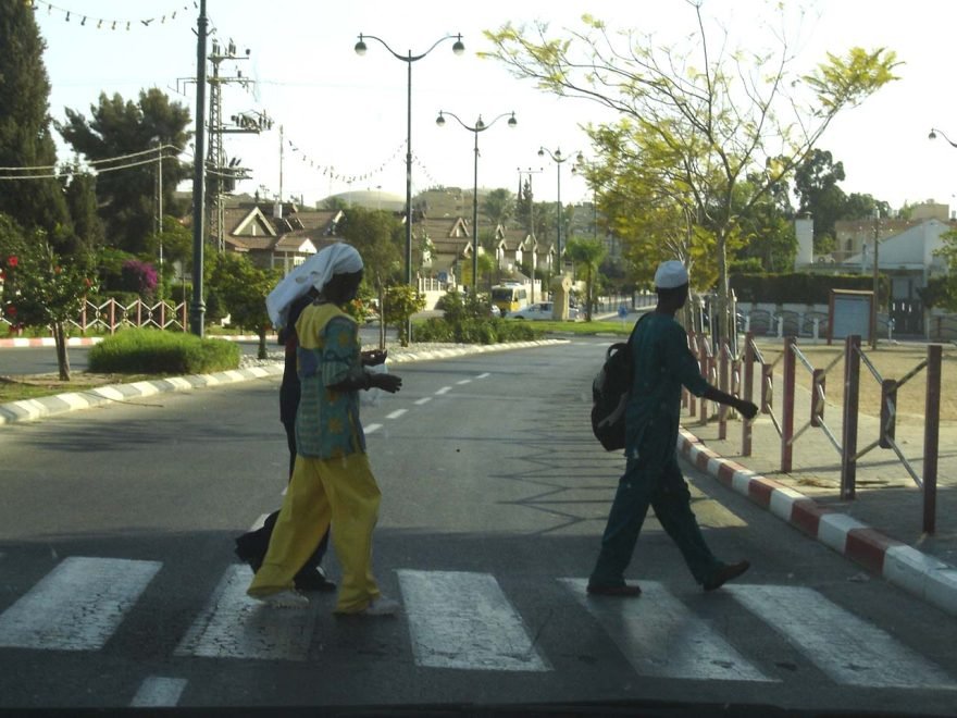 A photo of two Black Hebrew men crossing the street at a crosswalk.